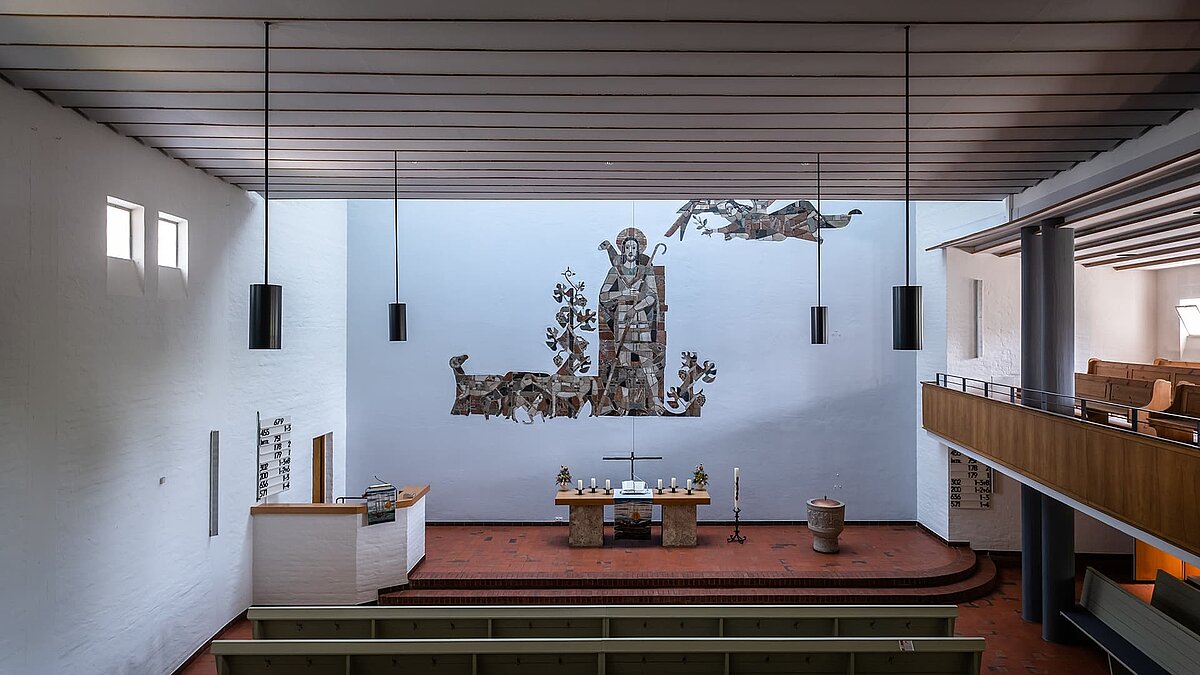 Interior of Pauluskirche in Traunreut featuring LAMILUX flat roof windows FE and a large wall mosaic in the altar area.