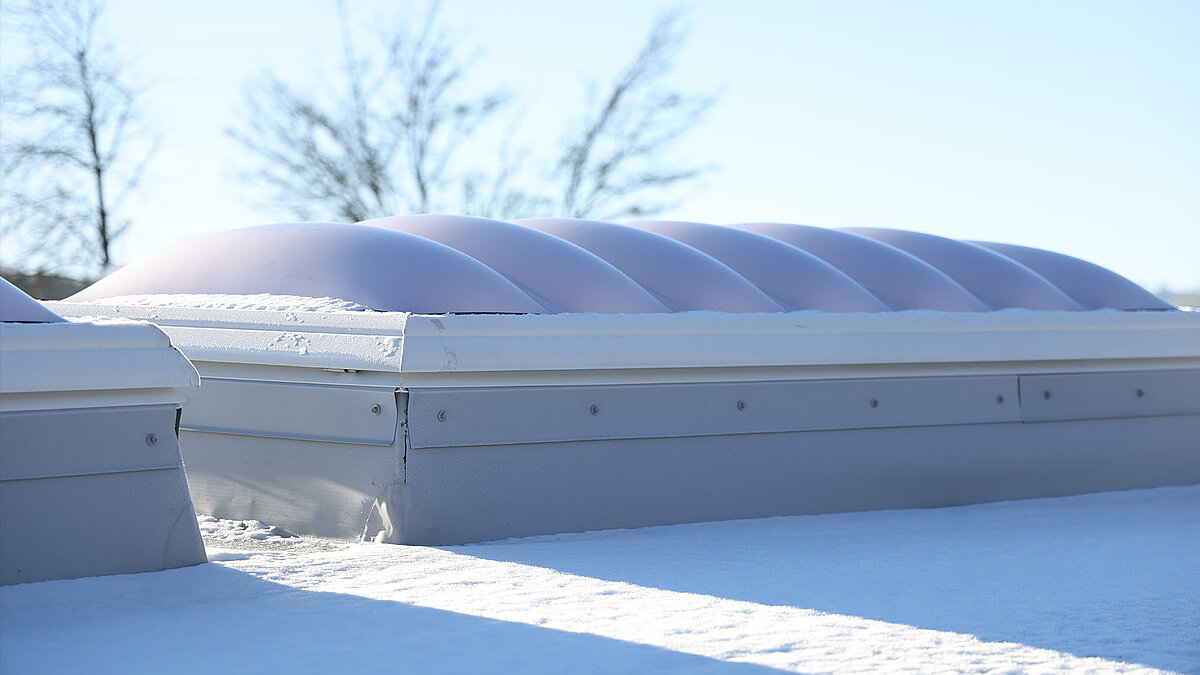 An undulating dome of light running along the roof of the ‘Ab in die Box’ building on Lake Diemelsee, covered in snow.