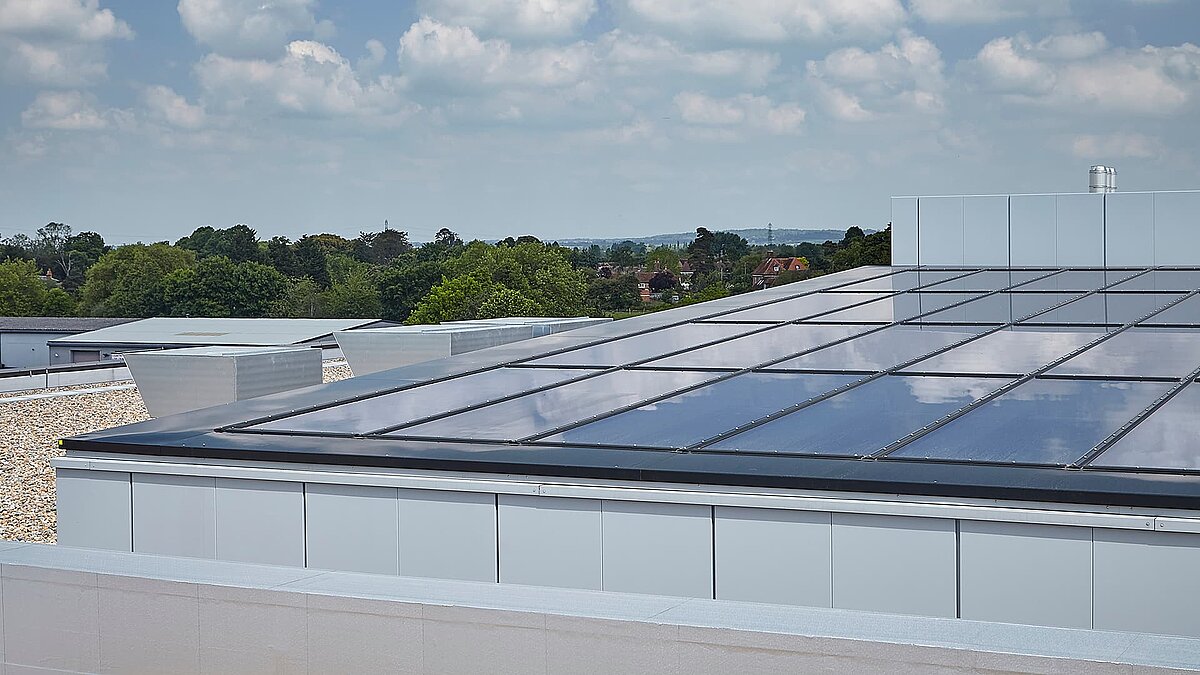 Modern glass roof of the commercial building in Milton Park, England, with reflective surface and cloudy sky in the background.