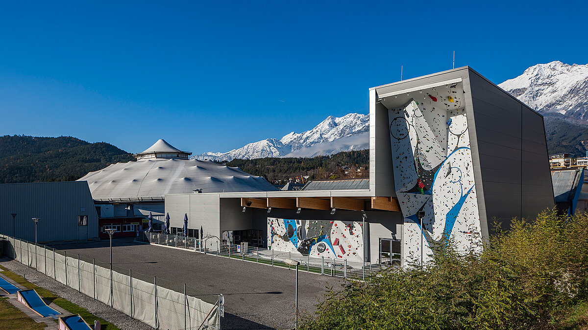 Modern climbing gym with colorful boulder wall and snow-capped mountains in the background