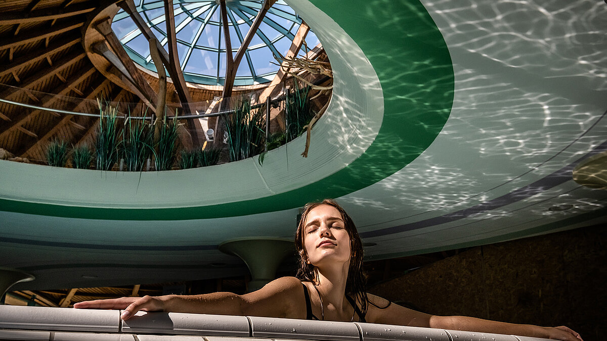 Woman relaxing in the water beneath the glass dome at the Solemar thermal spa in Bad Dürrheim.