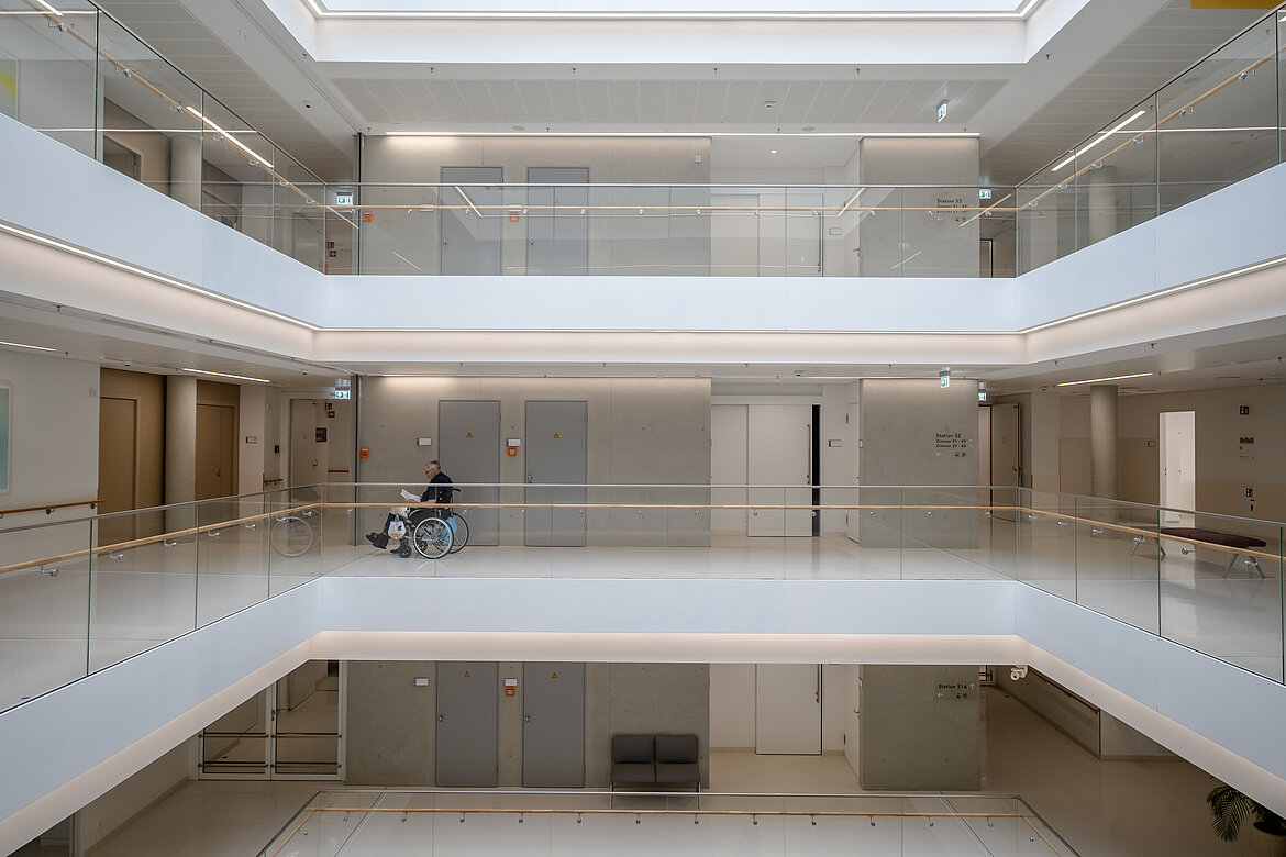 Modern, light-filled atrium with multiple floors and glass railings.