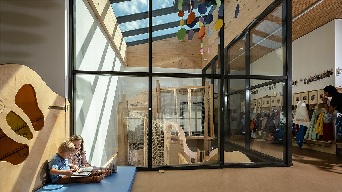 Emilio Daycare Center, with its modern design and glass roof, where children can relax and read in a light-filled common area.