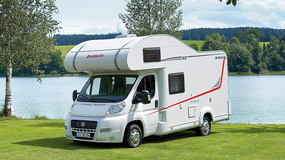 Alcove motorhome with typical protruding nose  Alcove motorhome by the lake