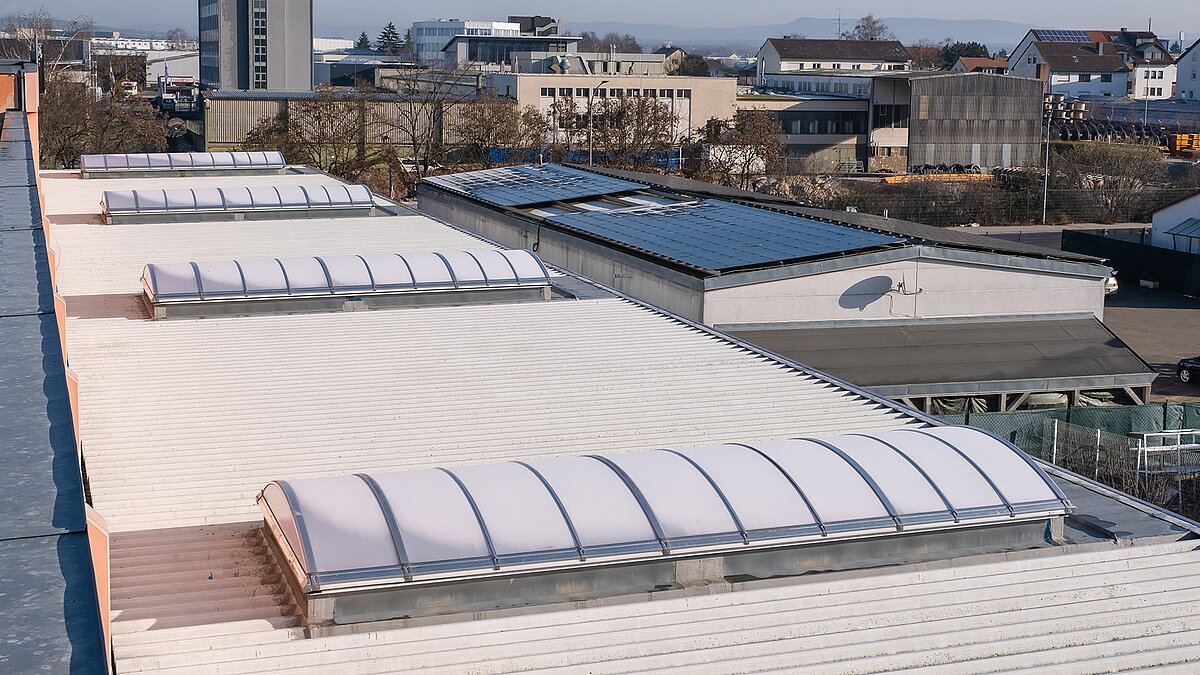 Roof of the OBI hardware store in Bamberg featuring curved skylight panels for natural lighting, surrounded by industrial buildings and solar panels.