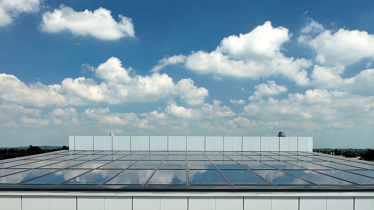 Glass roof of a modern commercial building in Milton Park, England, reflecting the blue sky with white clouds.