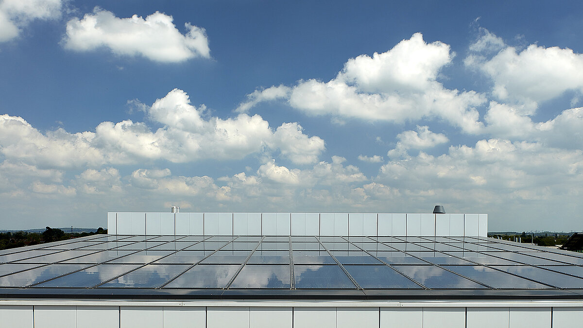 Glass roof of a modern commercial building in Milton Park, England, reflecting the blue sky with white clouds.