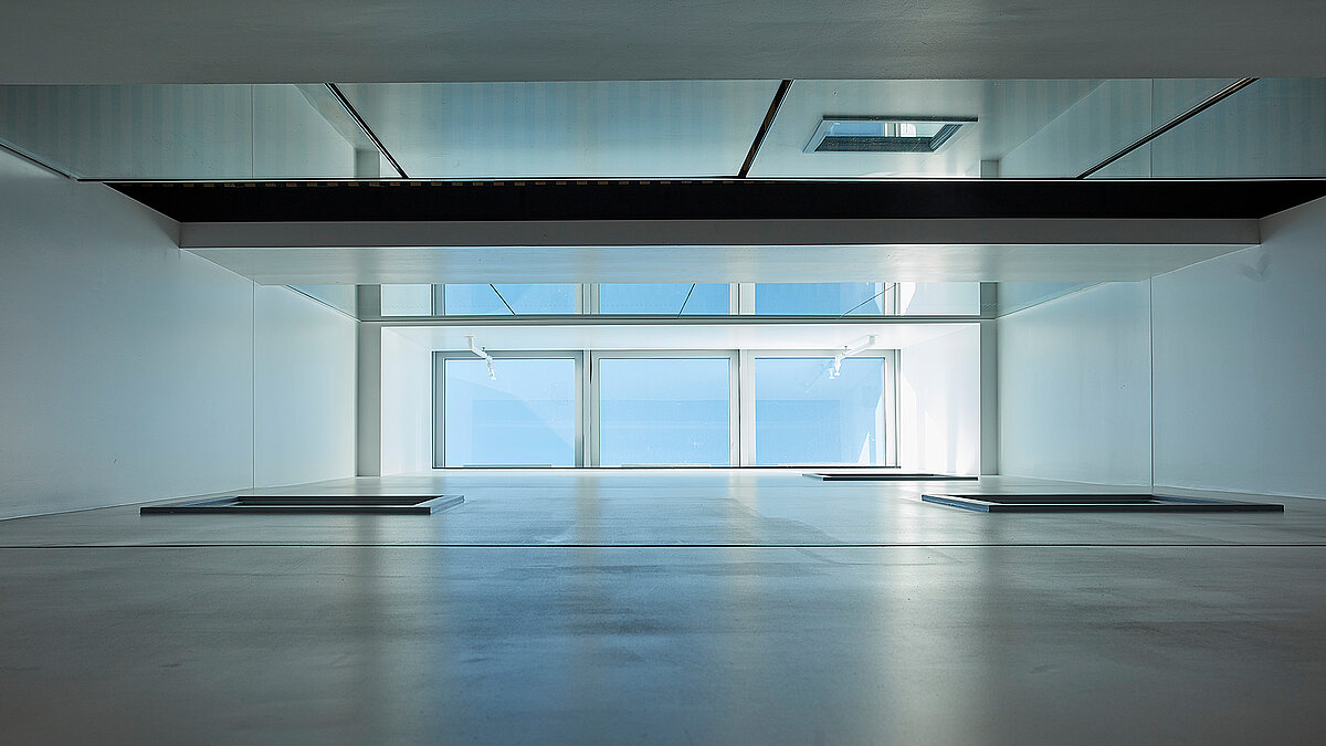 Modern interior space with large glass façade and continuous window band providing natural daylight