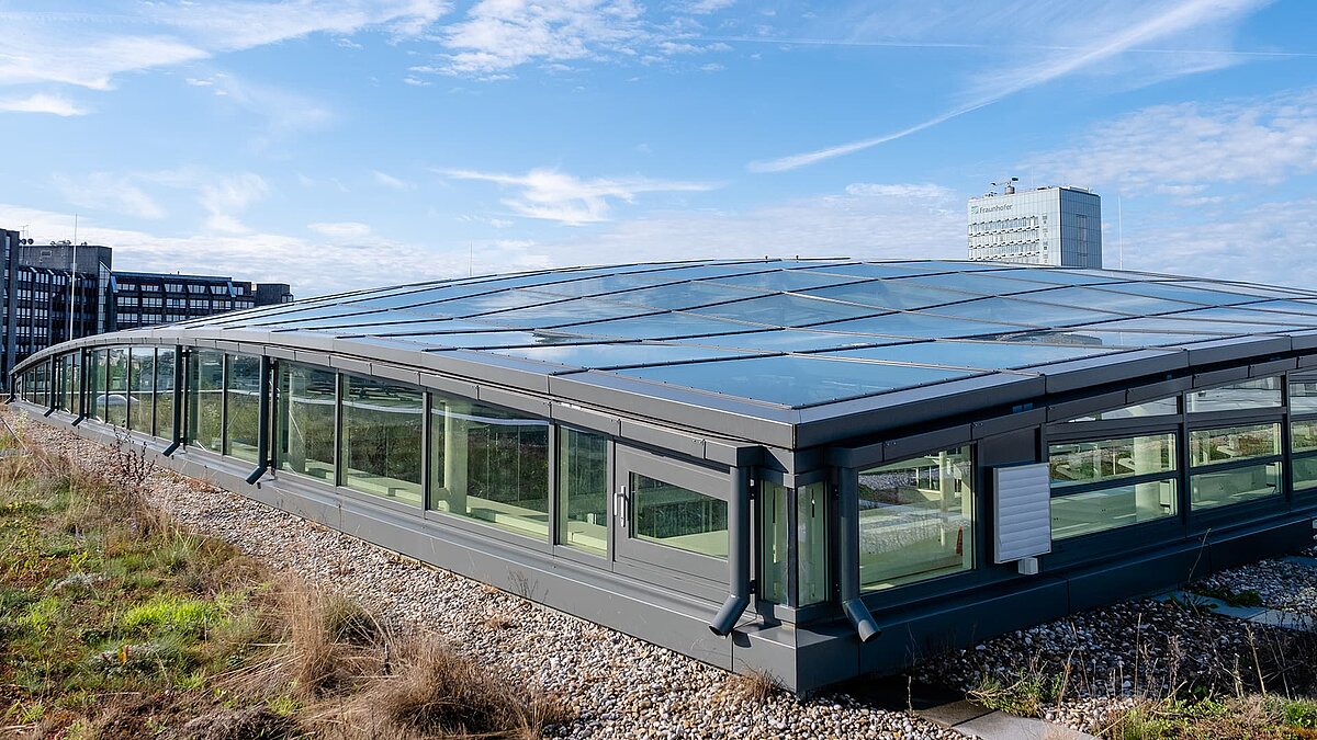 Exterior view of the roof of the TÜV Süd Group's Newton office building with modern glass roof and green surroundings.