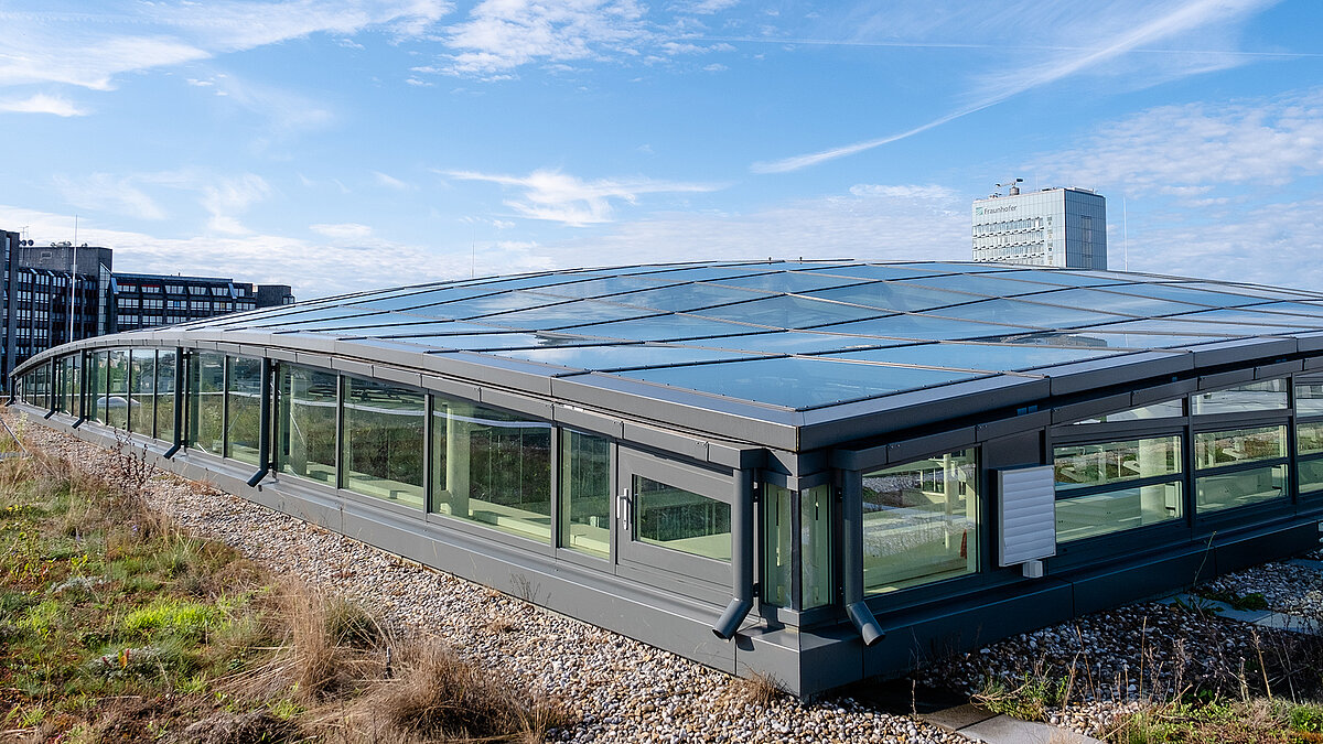 Exterior view of the roof of the TÜV Süd Group's Newton office building with modern glass roof and green surroundings.