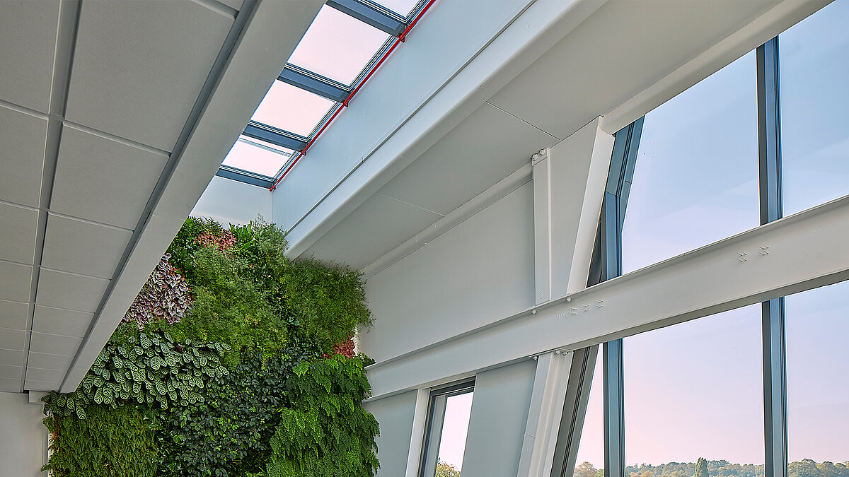 Interior view with LAMILUX Glass Roof PR60, white steel beams and green wall