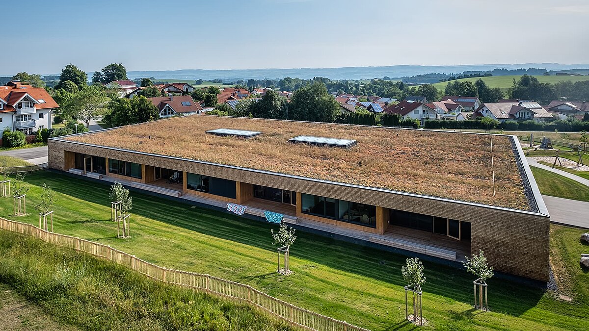 Wiggensbach daycare center with a green flat roof and large glass skylights for natural light.