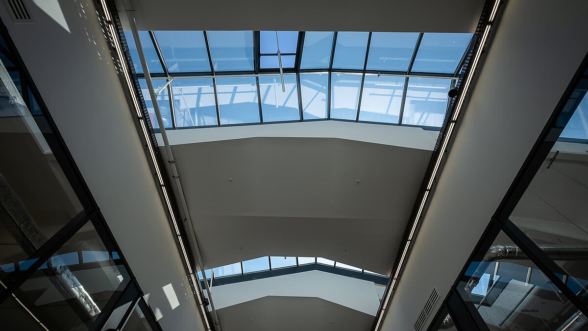 Interior view of the LAMILUX glass roof PR60 in the Outlet Centre Selb with blue sky and modern, light-flooded design.