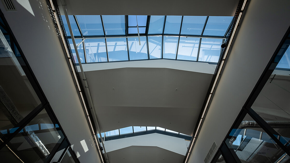 Interior view of the LAMILUX glass roof PR60 in the Outlet Centre Selb with blue sky and modern, light-flooded design.