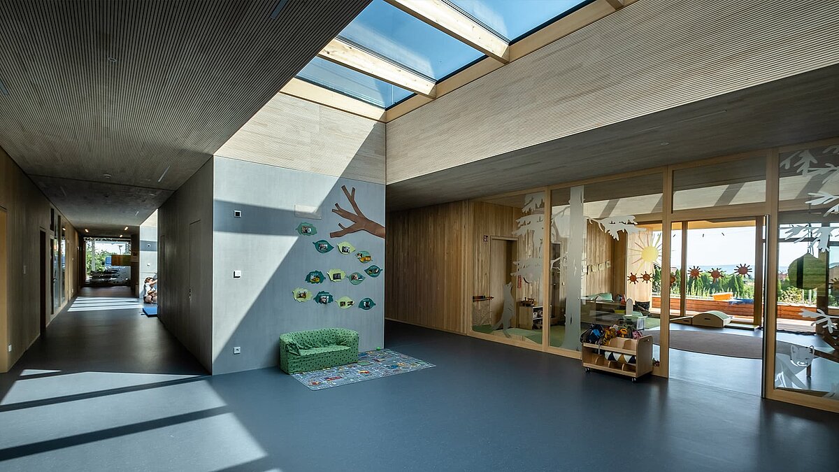 Interior of the Wiggensbach daycare center with large glass roofs providing natural light to the modern, light-filled space.