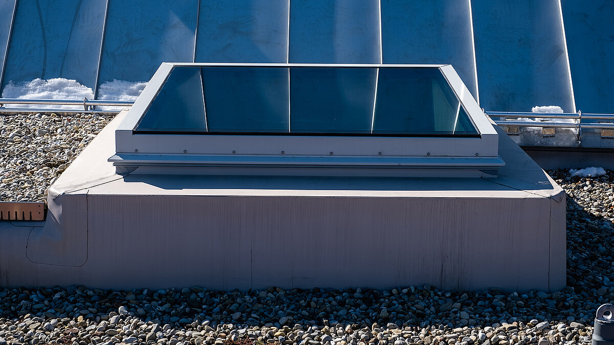 Flat roof of the Waltenhofen daycare center with a modern rectangular skylight and gravel surface.