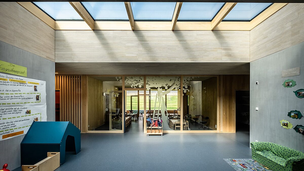 Interior of the Wiggensbach daycare center featuring large glass roofs that provide ample natural daylight.