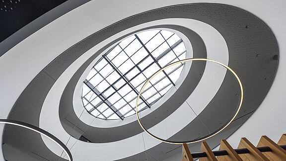 View upwards to the LAMILUX glass roof in the Breisgau competence center with modern ring lighting and architectural atrium.