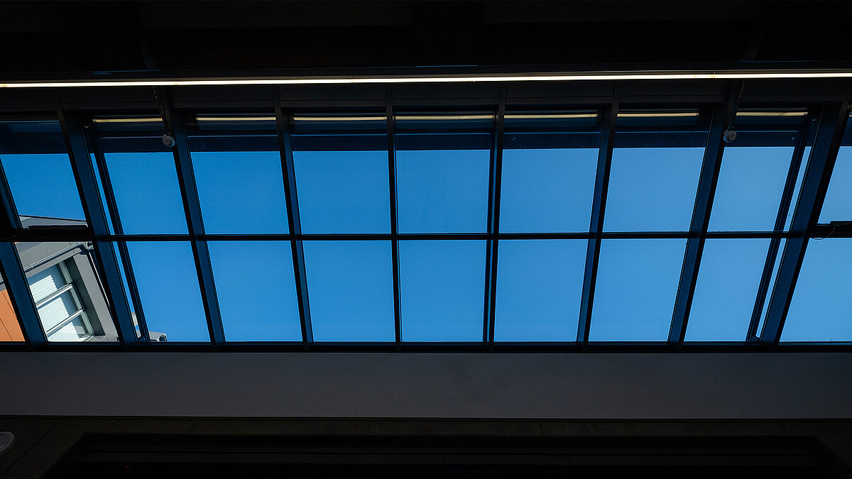 Upward view of the LAMILUX PR60 glass roof at the Rehau school center, showing the clear blue sky.