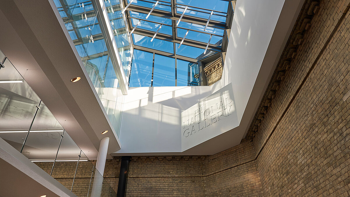 Glass roof with steel frame over bright interior with visible concrete walls