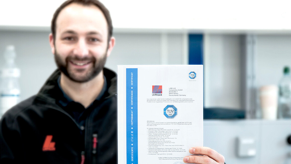 Man laughs and holds certificate up to the camera