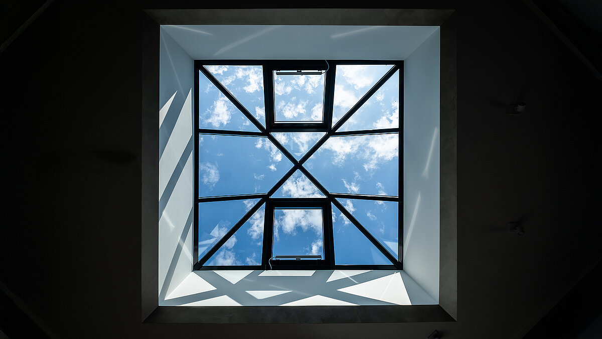 Glass pyramid in the new single-family house in Wichmannsdorf, view of blue sky with clouds, light-filled living space.