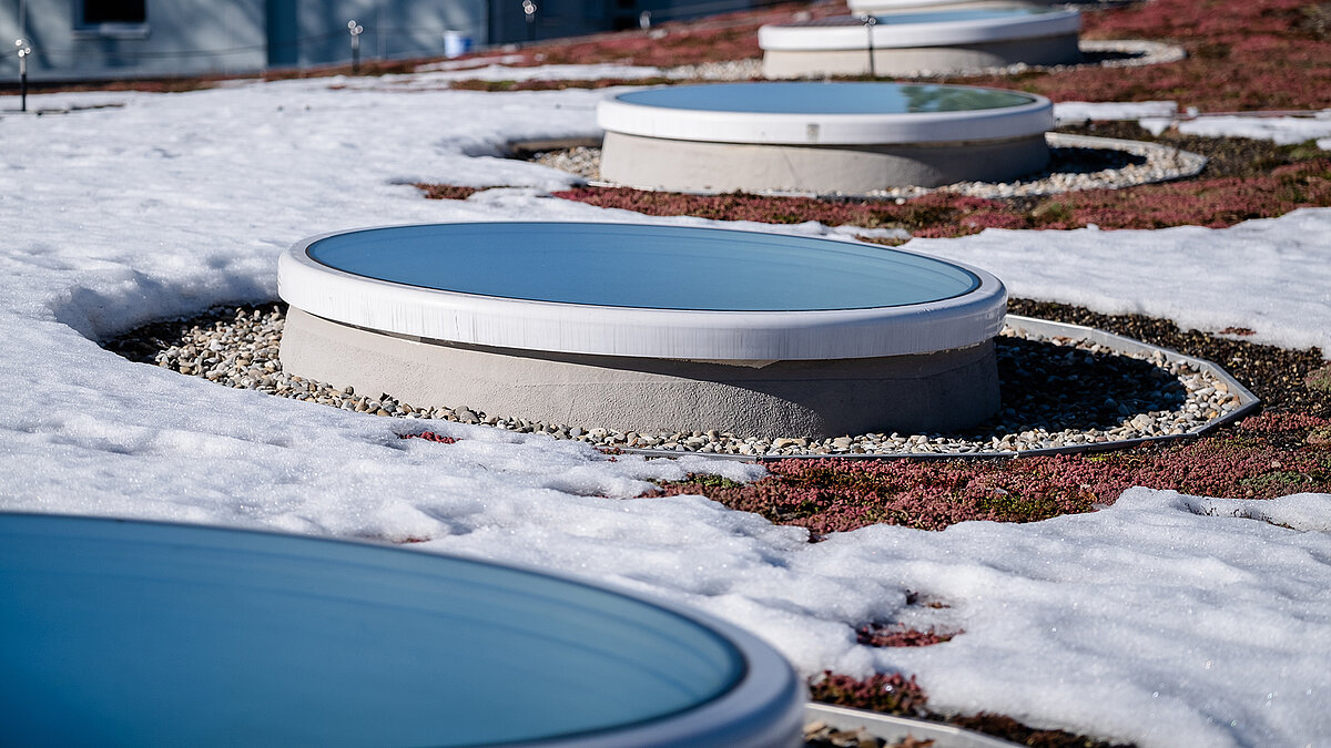 Round flat roof windows on the green and snow-covered roof of St. Severin Kindergarten.