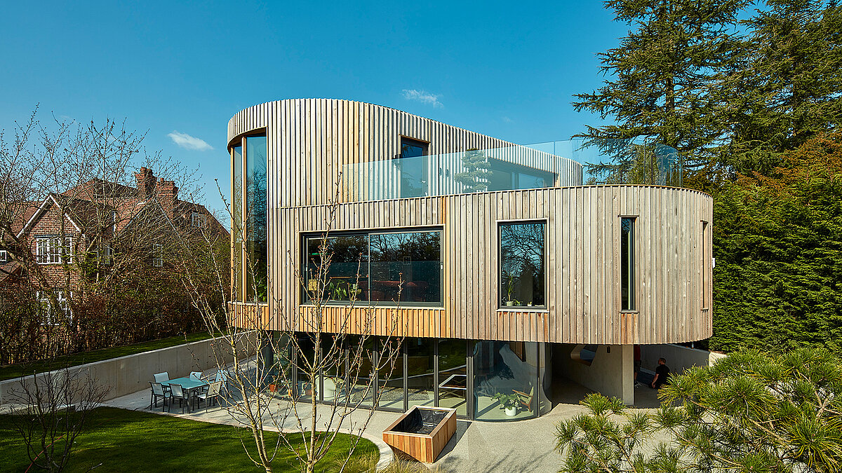 Modern residential house with curved wooden facade, large glazing and terrace