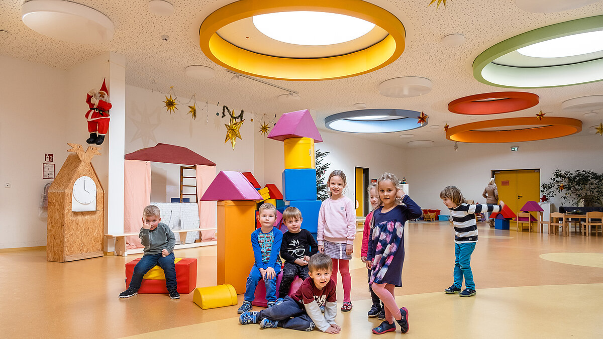 Happy children play in the Glückliche Zukunft daycare centre in Sömmerda, with colourful round ceiling windows and playful furnishings.