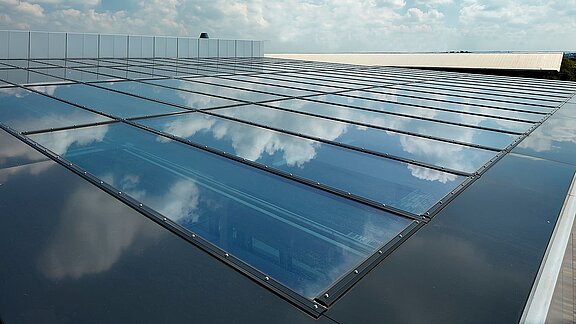 Glass roof of the commercial building in Milton Park, England, reflecting the sky and clouds on its surface.