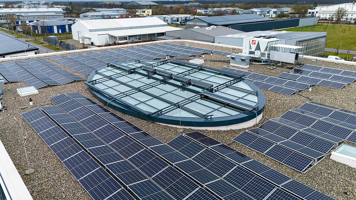 Flat roof of the Breisgau Competence Center with solar panels and large oval glass roof in the middle