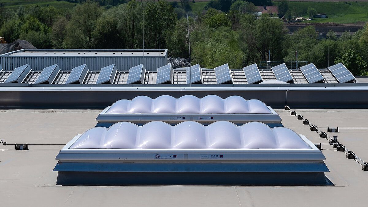 LAMILUX F100 W skylights on the roof of the Unglehrt construction company's production hall, with LAMILUX B continuous rooflights and solar panels in the background.