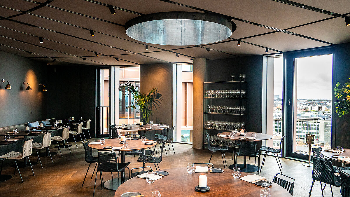 Modern restaurant with round tables, large skylight and panoramic city view