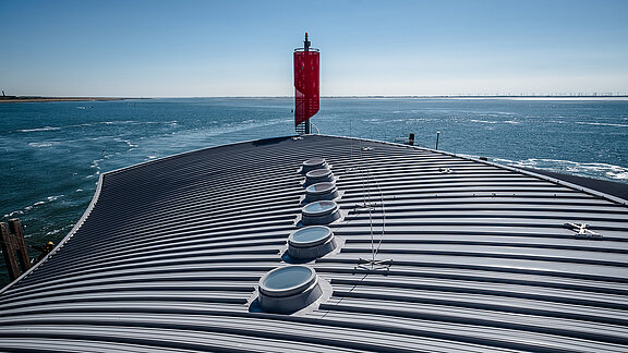 Roof of the Norderney ferry terminal featuring round skylights for natural daylight, with the sea.