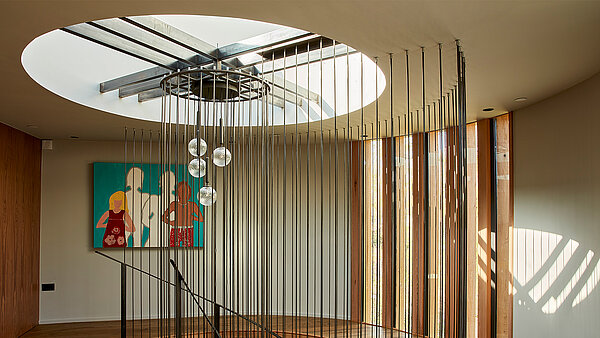 Interior with round LAMILUX flat roof window and decorative wooden slats