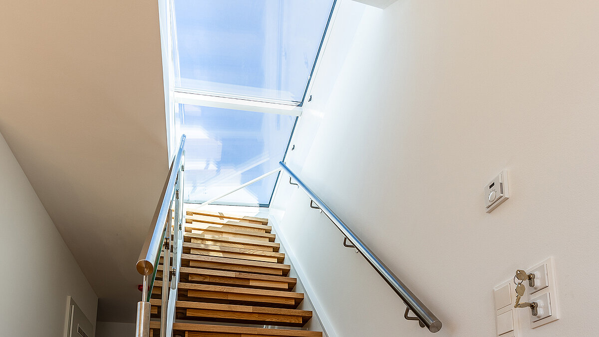 Staircase in a residential house in Korneuburg with flat roof access and large glass roof for natural lighting.
