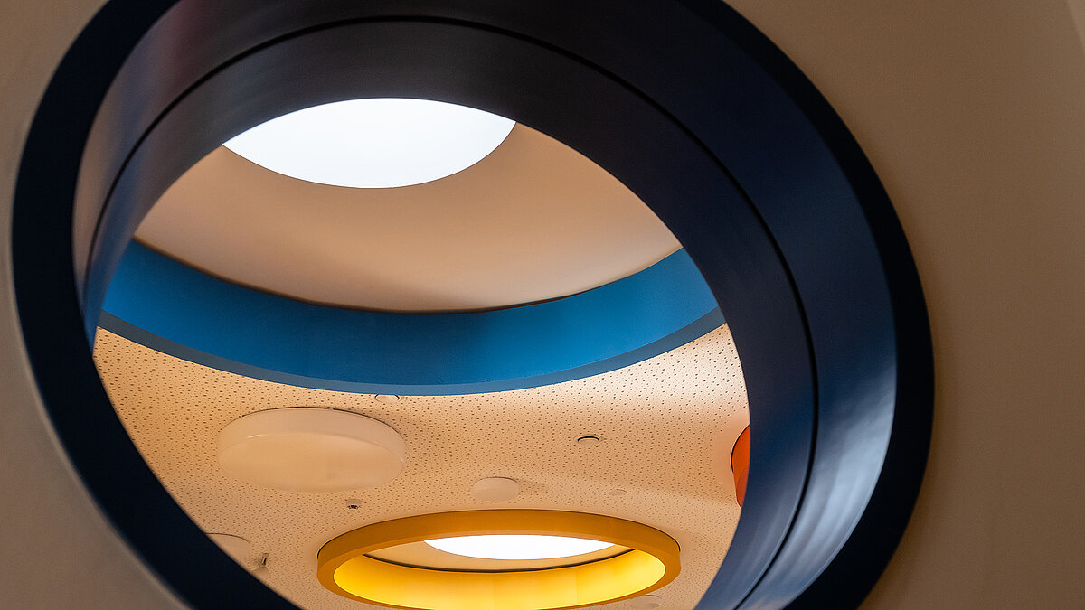 Interior view of the "Glückliche Zukunft" daycare center in Sömmerda featuring round, colorful ceiling openings and skylights.