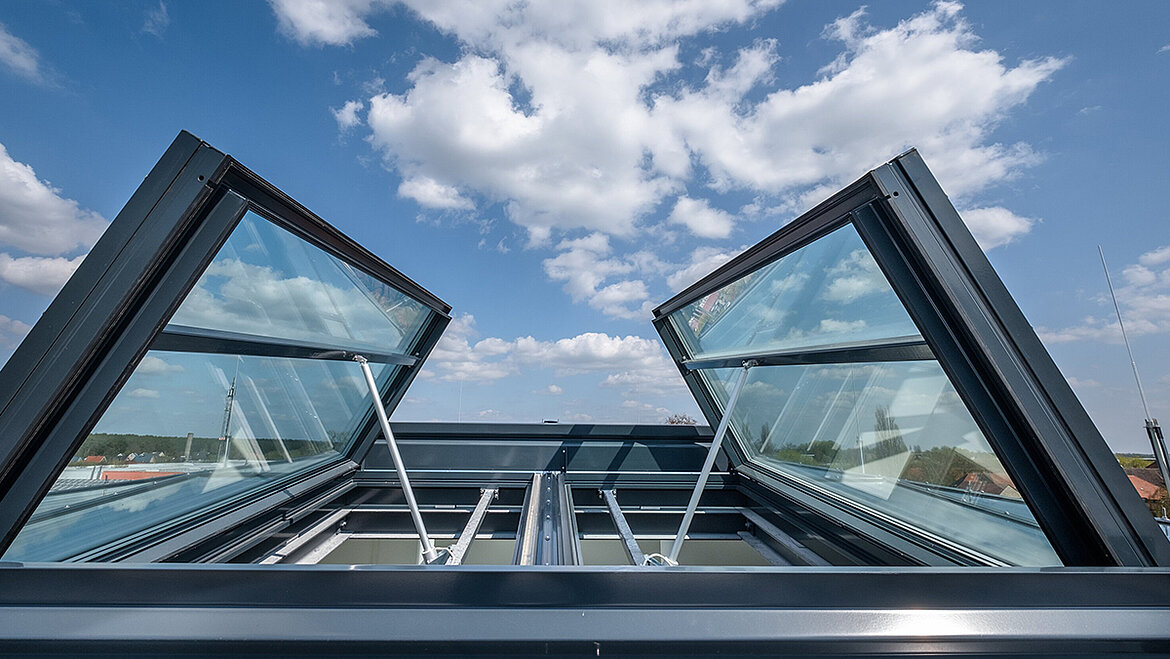 An open skylight with an aluminium frame and a blue sky