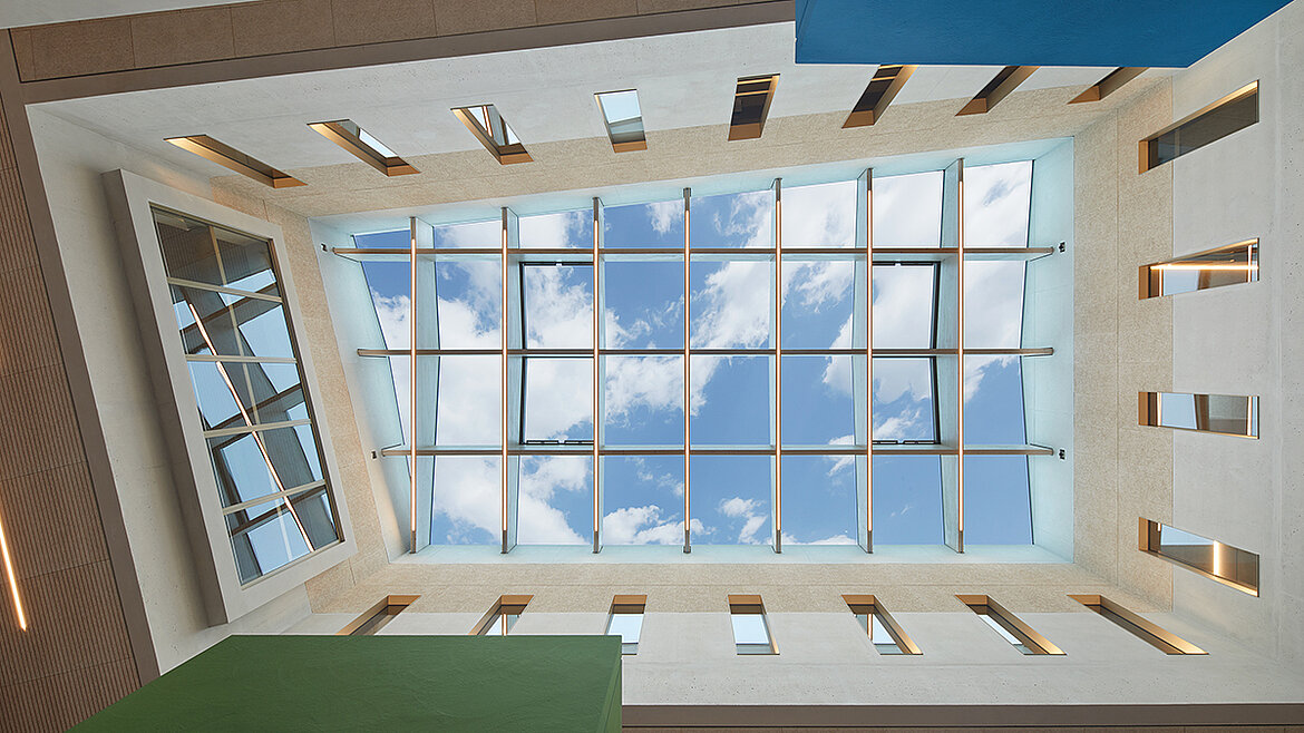 Modern atrium with a glass roof and blue sky
