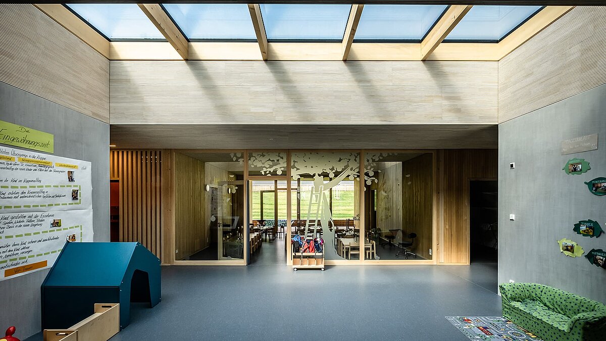 Interior of the Wiggensbach daycare center featuring large glass roofs that provide ample natural daylight.