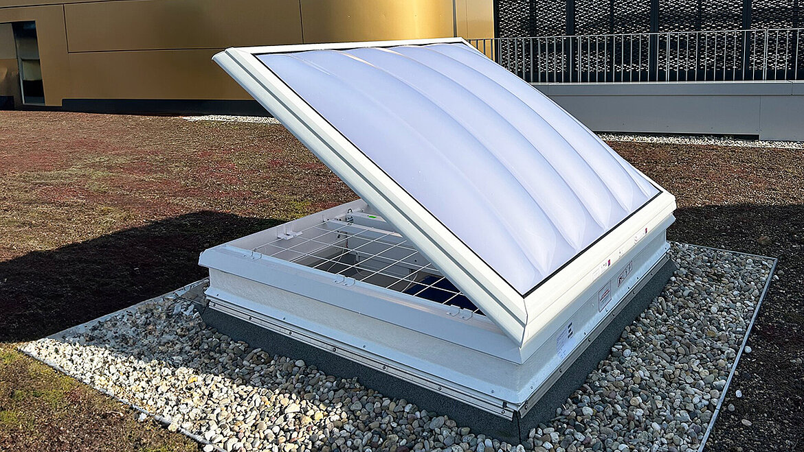 Open Rooflight Dome with a white polycarbonate dome on a flat roof, with a gravel surround and a green roof