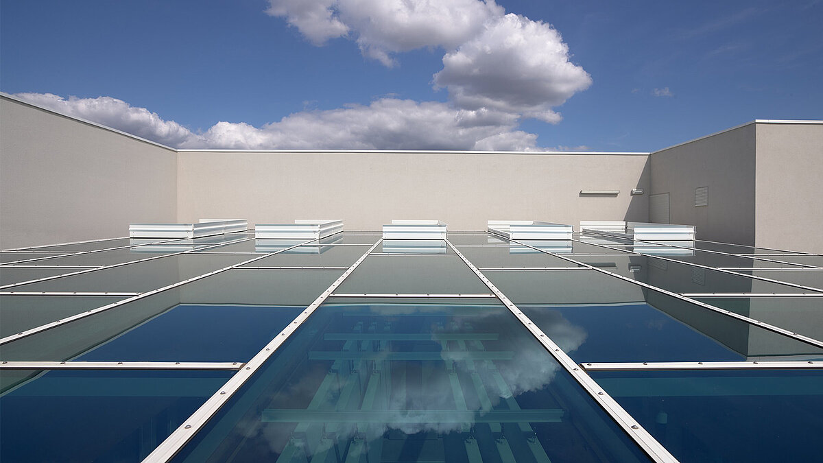 Flat roof with large glass roofs and modern industrial architecture under blue sky
