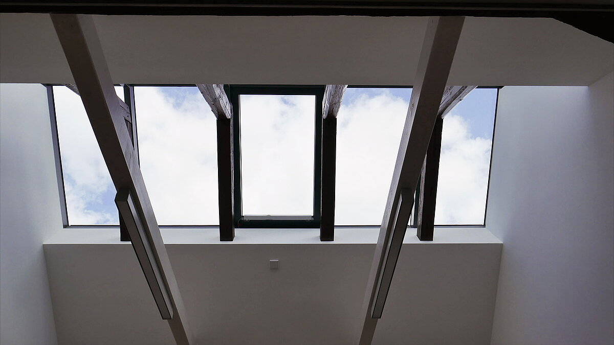 Glass roof with wooden beams and modern lighting at Leibniz University Hannover, view of the sky.
