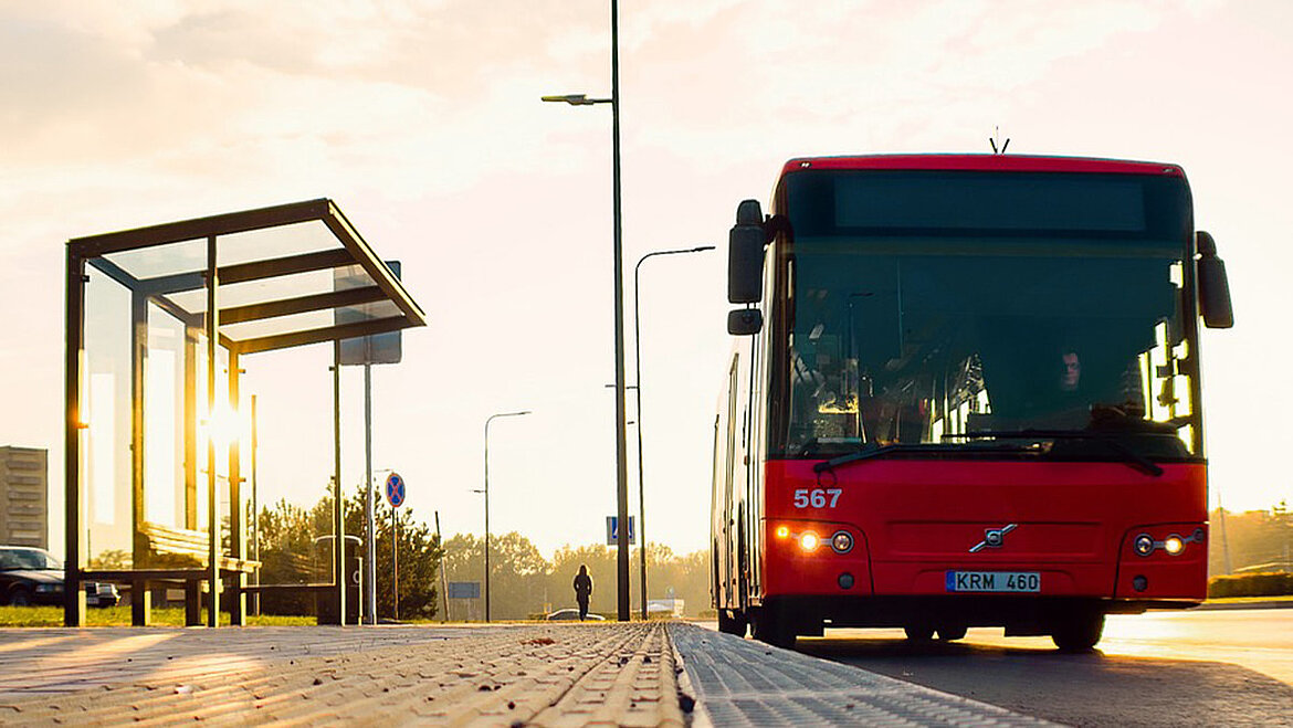 A red city bus at a bus stop