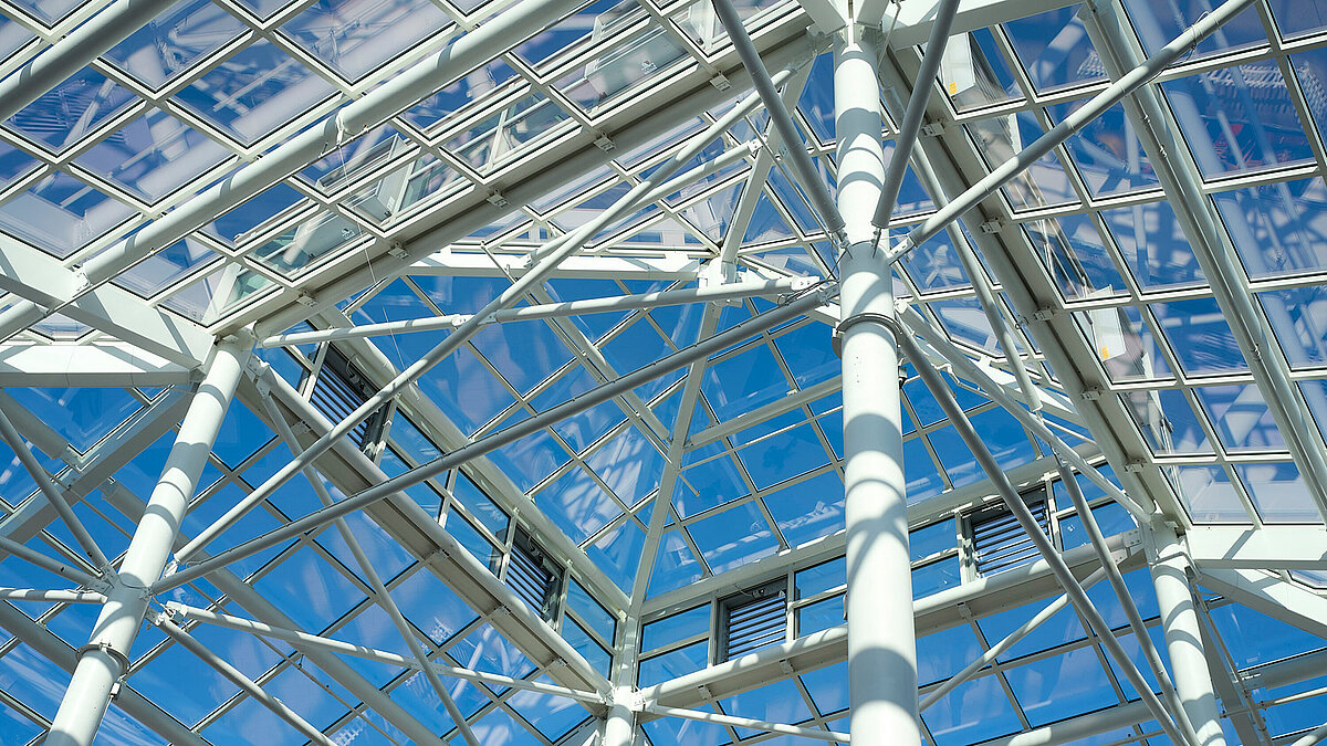 Close-up of steel structure of a glass roof with grid frame and blue sky in the background