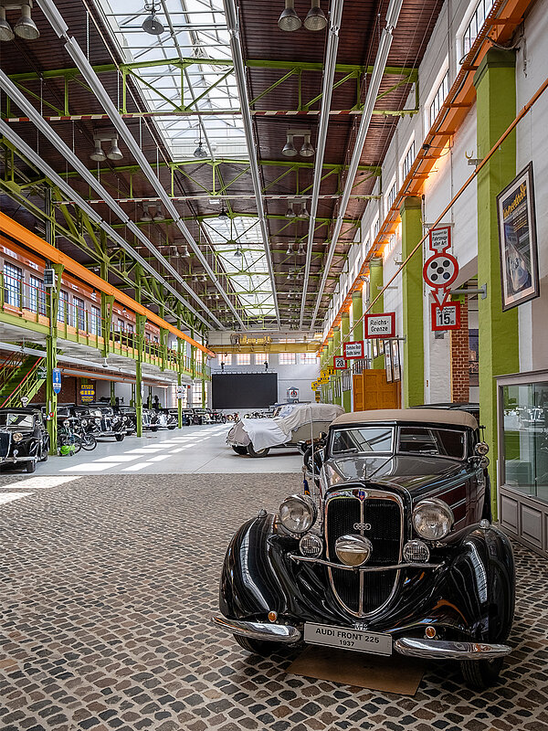 Ein Oldtimer im Vordergrund der Eventhalle Zündmagnet in Wurzen mit historischen Backsteinwänden, großen Glasfenstern und Oberlichtern.