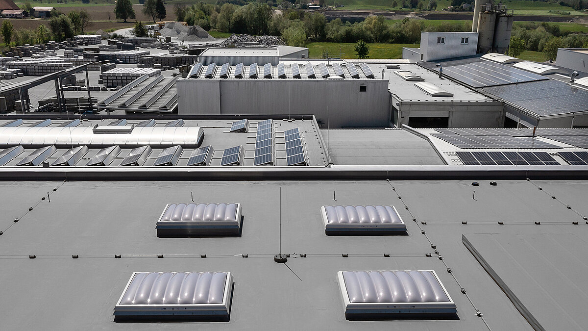 Roof view of the production hall of the Unglehrt construction company with LAMILUX F100 W skylights, B light bands, and solar panels.