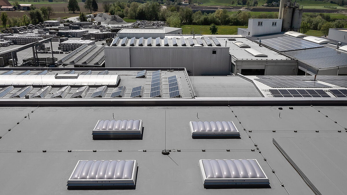 Roof view of the production hall of the Unglehrt construction company with LAMILUX F100 W skylights, B light bands, and solar panels.