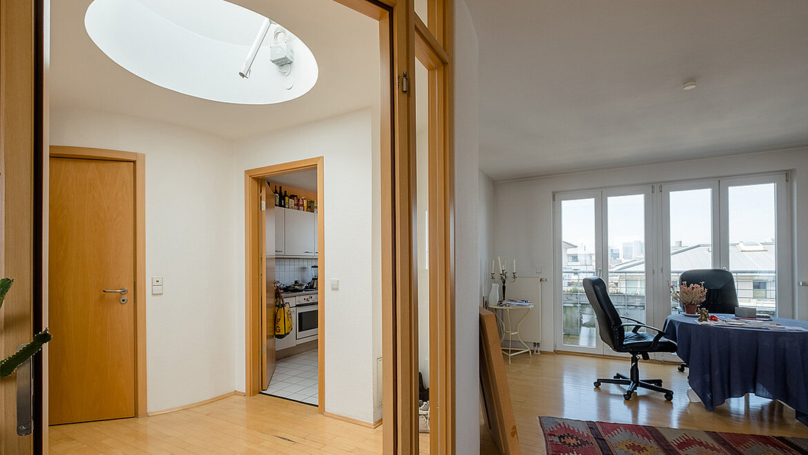 Apartment hallway with a round flat-roofed window and natural light