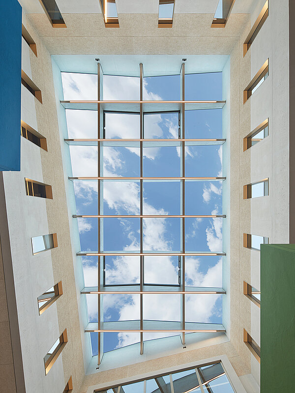 Blick von unten auf ein Flachdach Fenster mit blauem Himmel und ein paar weißen Wolken darüber